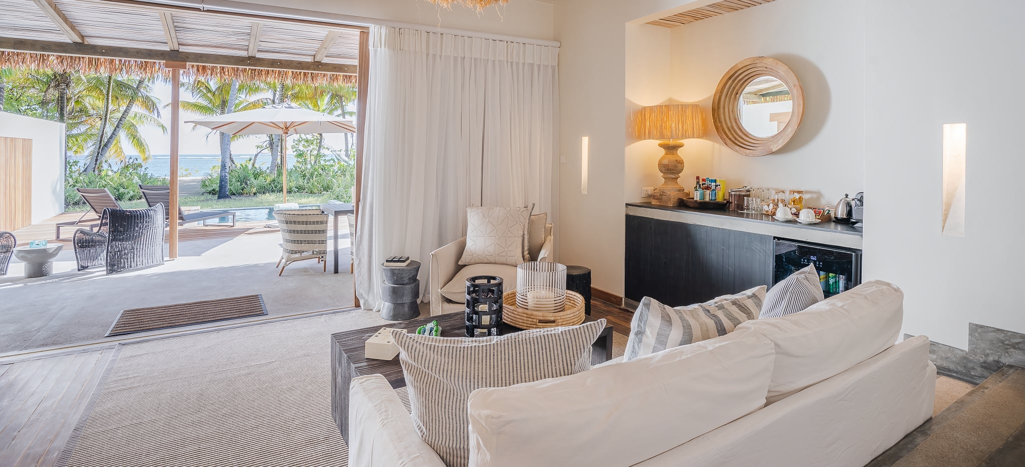 Das Wohnzummer einer Beach Villa im Hotel Alphonse Island Retreat auf den Seychellen, mit dem Blick über den Pool auf den Strand und Meer