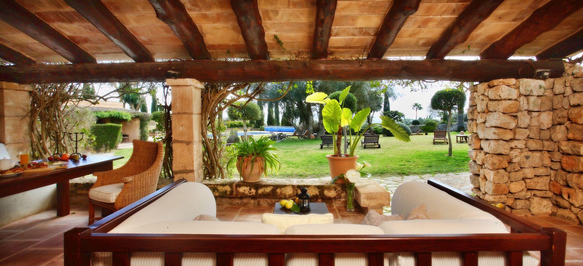 Eine Terrasse mit einer gemütlichen Couch und Blick auf einen mediterranen Garten