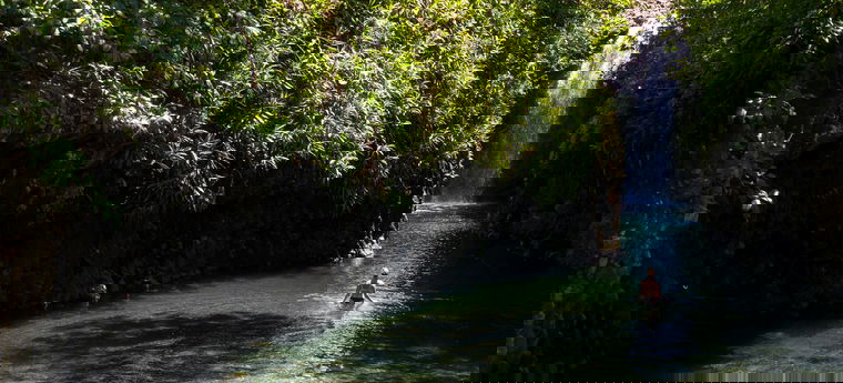 Eine Frau badet nahe einem Wasserfall auf Fidschi