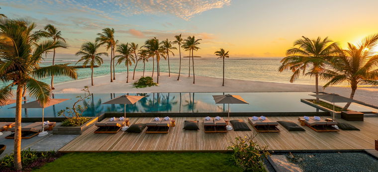 Poolbereich der Malediven-Resortinsel Alila Kothaifaru bei Sonnenuntergang